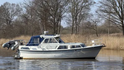wit motorjacht op rustig water bij riet