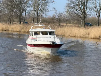 motorjacht op rivier met oever en bomen