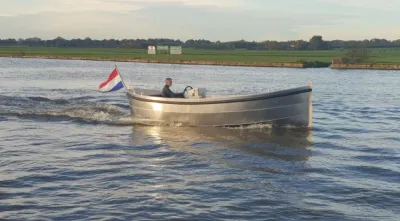 zilveren sloep op rivier met schipper