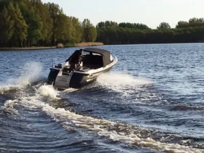 sloep vaart op meer met bomen op achtergrond