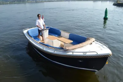 open sloep met stuurman op het water