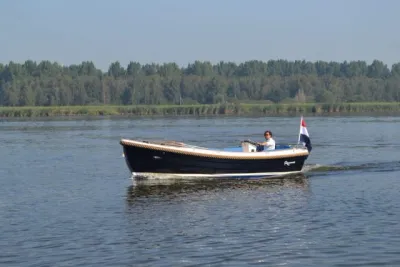 sloep op rustig water met bomen op achtergrond