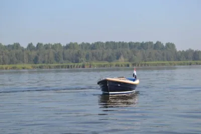 sloep op rustig water met oever en bomen