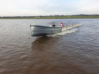 open sloep op rivier met Nederlandse vlag