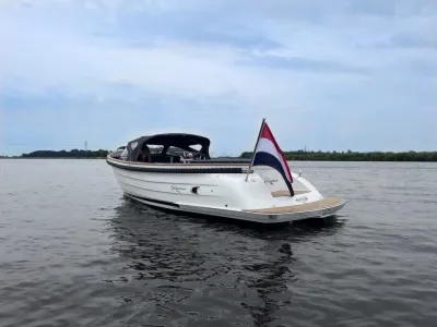 witte sloep op rustig water met vlag