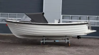 witte sloep op trailer bij bedrijfspand