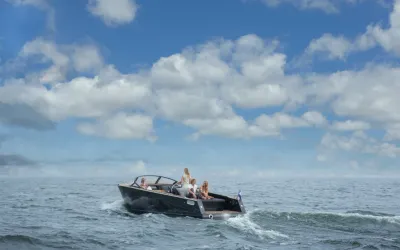 zwarte sloep met mensen op open water