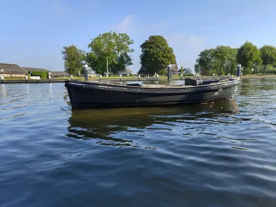 zwarte sloep op kalm water bij kade
