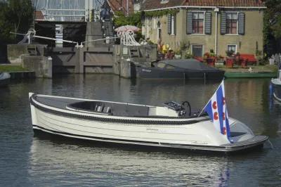witte sloep in kanaal bij brug en huizen