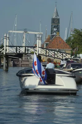 achterzijde sloep met vlag en brug op kanaal