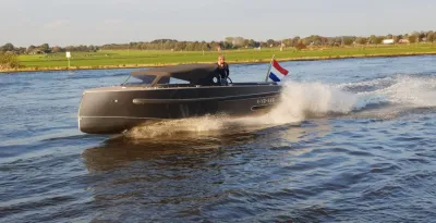sloep varend op rivier met Nederlandse vlag