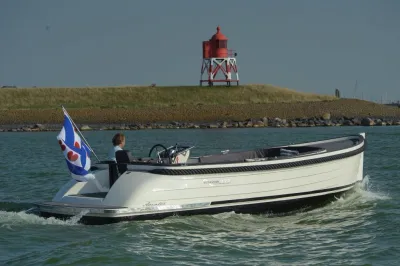 sloep op water met vuurtoren op achtergrond