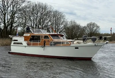 motorkruiser op rustig water bij boomrijke oever