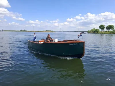Groene sloep op rustig water met persoon aan boord