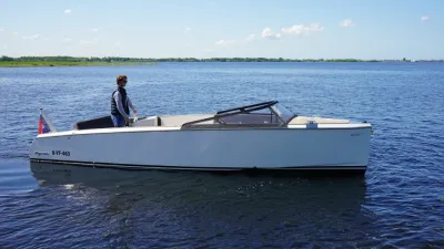 witte sloep op rustig water met stuurman
