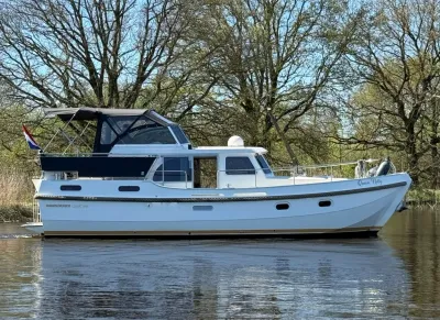 wit motorjacht op rustig water bij bomen