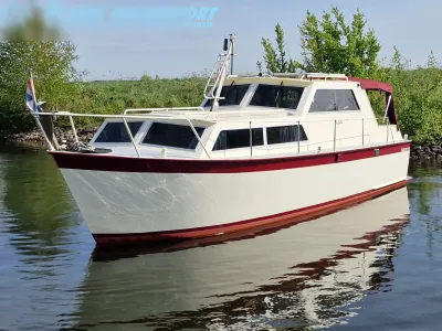 motorjacht in water bij begroeide oever