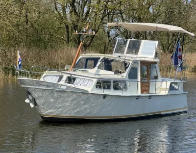 motorkruiser op rustig water met bomen op achtergrond
