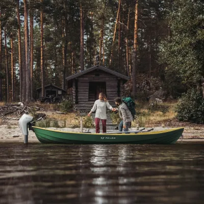 groene roeiboot bij houten hut en bos