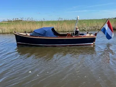 sloep op kanaal met persoon en Nederlandse vlag