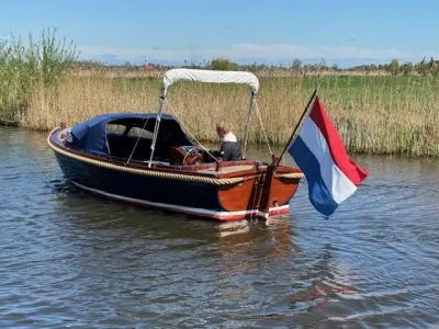 houten sloep op rustig water met vlag