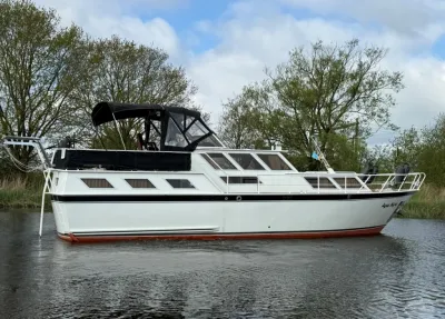 wit motorschip op stil water bij bomen