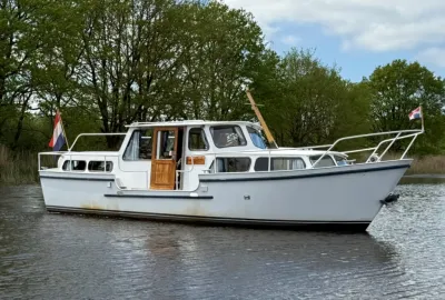 wit motorjacht op rustig water bij bomen