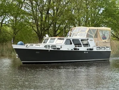 motorkruiser op rustig water bij groene oever