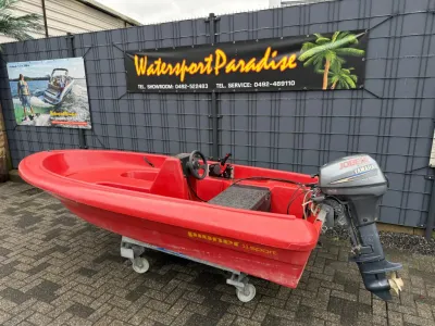 rode open boot met buitenboordmotor bij hek