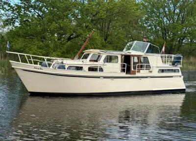 witte kruiser op rustig water met bomen