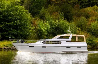 witte motorboot op kalm water bij groene oever