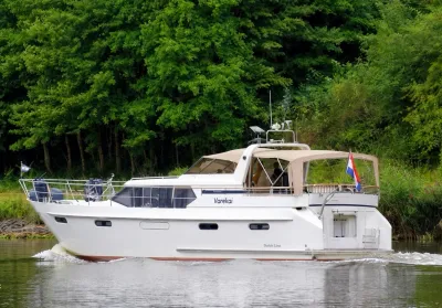 motorjacht op rustig water langs groene oever