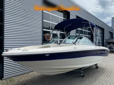 witte motorboot met blauwe bimini bij showroom