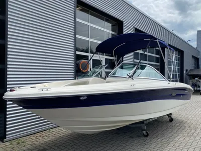 witte motorboot met blauwe bimini bij showroom