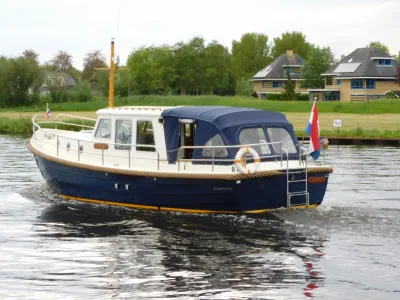 Motorboot varend op een kanaal bij huizen