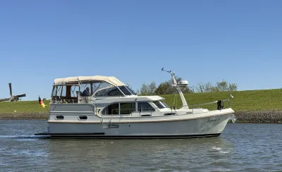 motorjacht bij grasdijk met molen op achtergrond