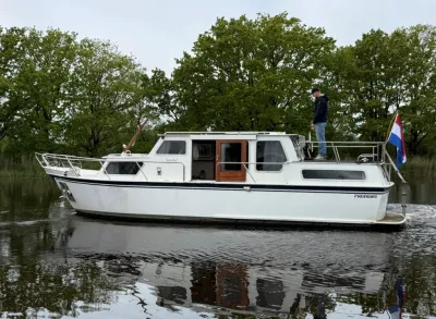 witte motorkruiser op stil water met bomen