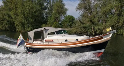 cabinsloep op water met bomen op de oever