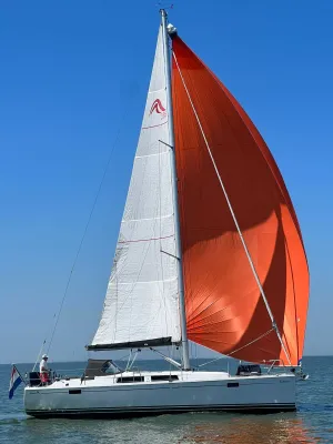 zeiljacht met witte mast en oranje spinaker