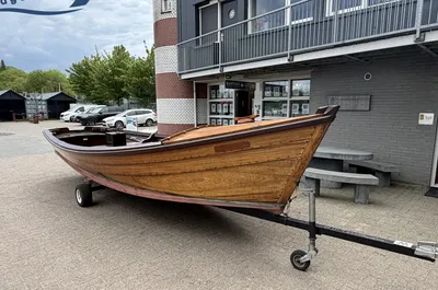houten sloep op trailer bij bedrijfsgebouw