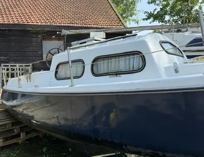 zeilboot zonder mast naast schuur