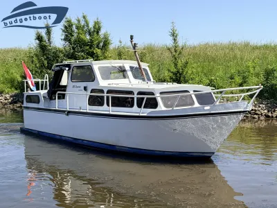 witte motorboot bij oever met gras en bomen
