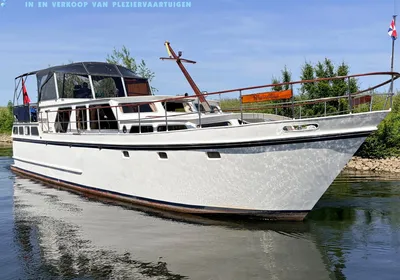 witte motorboot op water bij groene oever