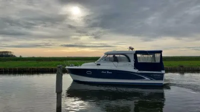kajuitmotorjacht in kanaal bij bewolkte lucht