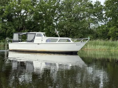 witte motorboot op rustig water met bomen
