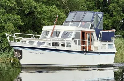 wit motorjacht op rustig water bij bomen