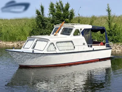 witte kajuitmotorboot op water bij oever