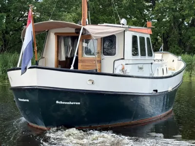 kotter op water langs groene oever