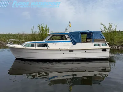 wit motorjacht liggend in het water langs oever