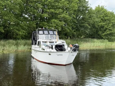 wit motorjacht op water bij riet en bomen